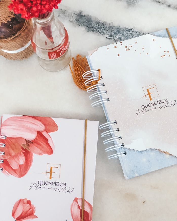 Crafting Captivating Headlines: Your awesome post title goes here Flat lay of trendy 2022 planners with floral designs and a Coca-Cola bottle on a marble background.