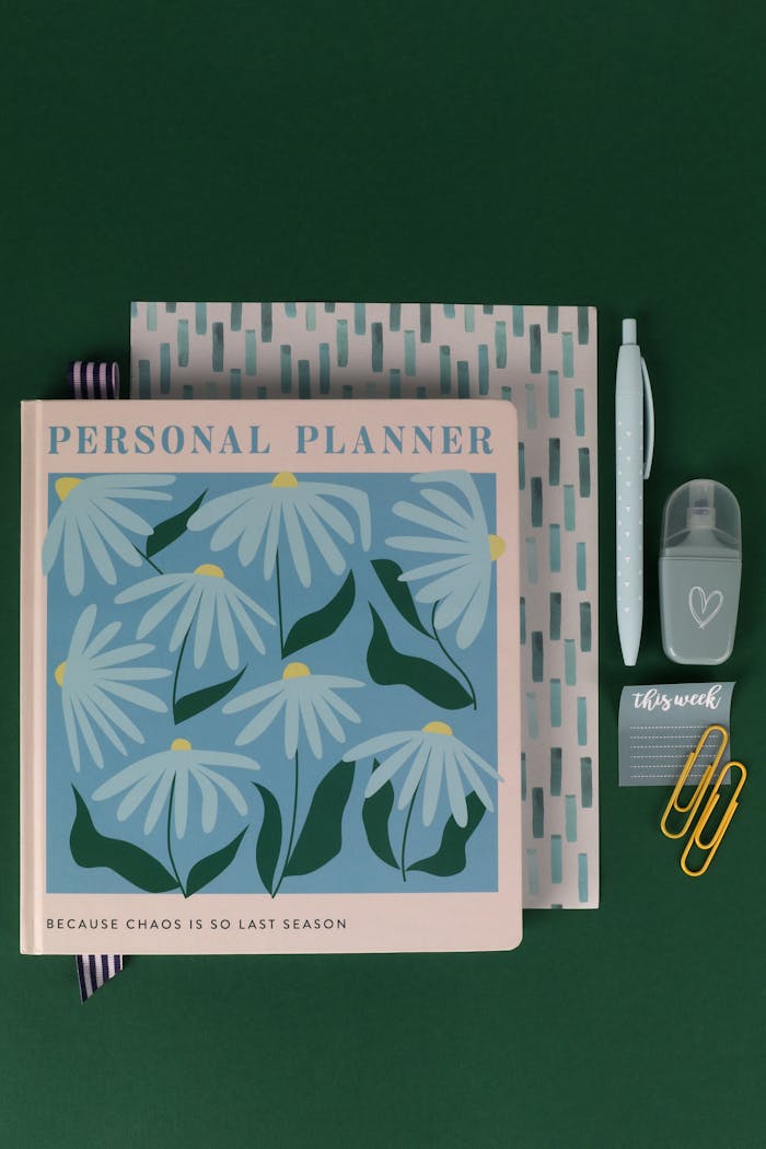our-story Stylish personal planner with floral design alongside stationery items, perfect for organization.