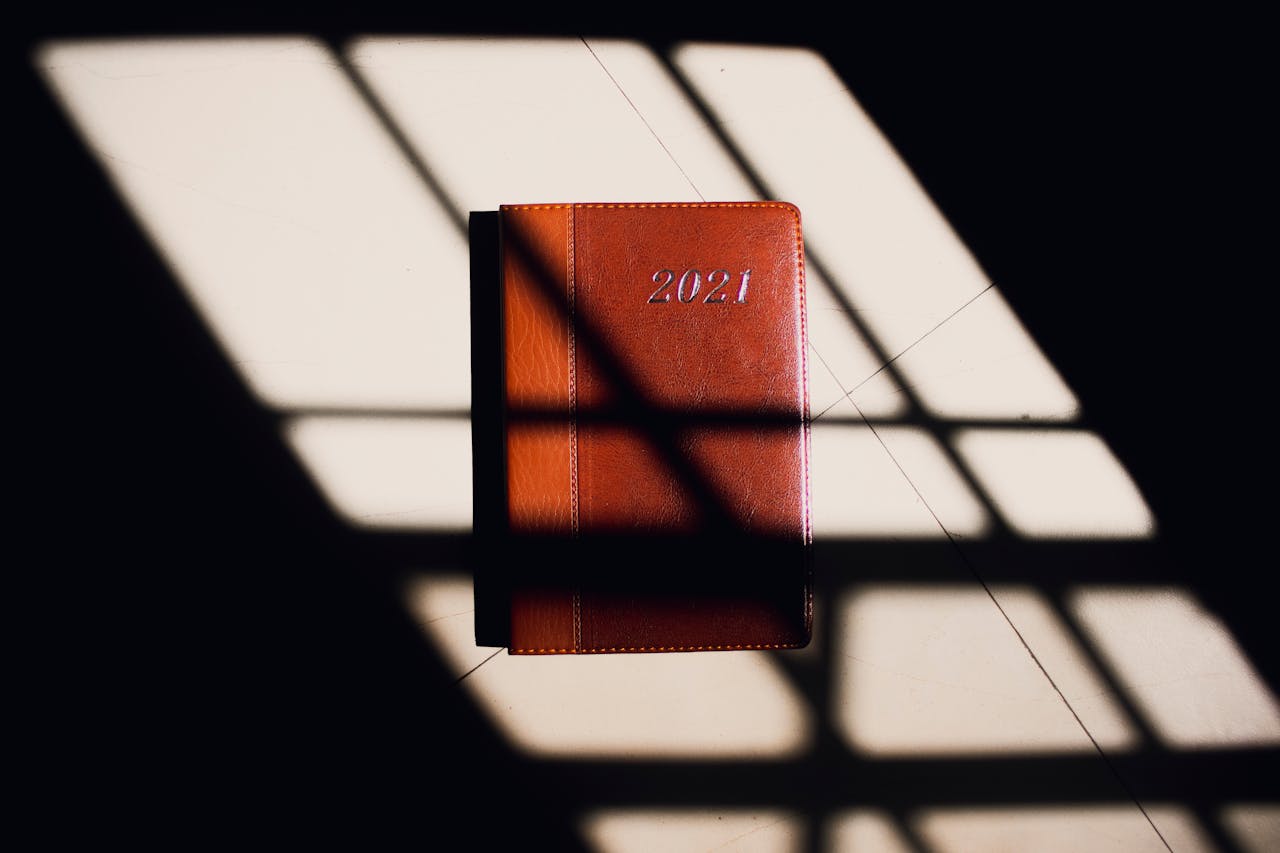 The Art of Drawing Readers In: Your attractive post title goes here Leather 2021 planner in striking shadows from a window grid, creating a minimalist aesthetic.